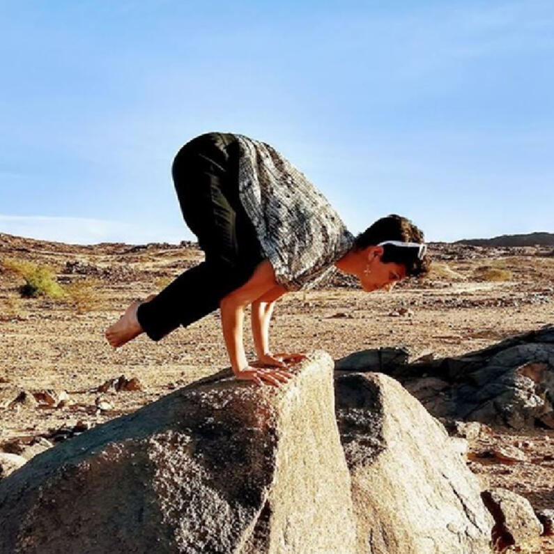 Katherine against a desert background doing the crow position with blue sky